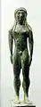Estatuilla votiva realizada en bronce, de un joven desnudo con los brazos a los lados, proveniente de Chiusi (550-530&nbsp;a.&nbsp;C.).