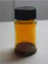 A small capped jar a quarter filled with a very dark liquid