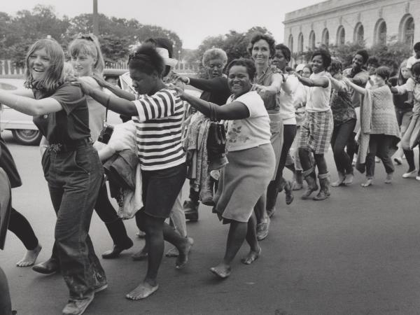 Black and white image of women walking in a line 