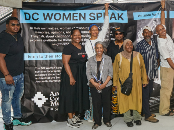Group of women standing in front of a DC Women Speak banner