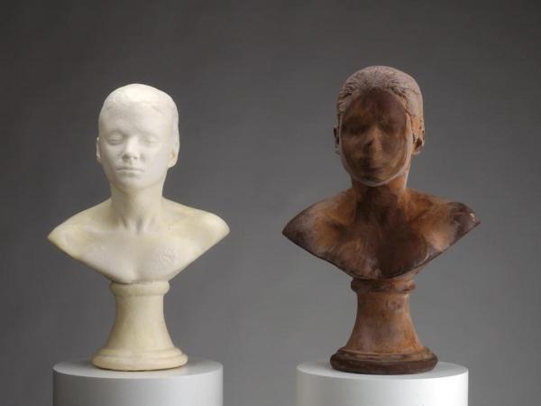 Two busts of self-portrait of artist Janine Antoni - one made of white soap, one made of chocolate. Her features have been worn down by bathing the soap and licking the chocolate.
