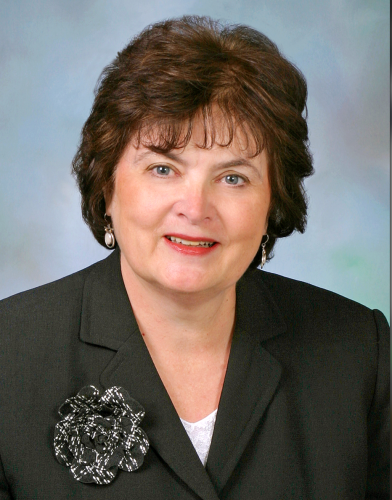 Jeanne Hubbard wearing a dark suit against a light gray background.