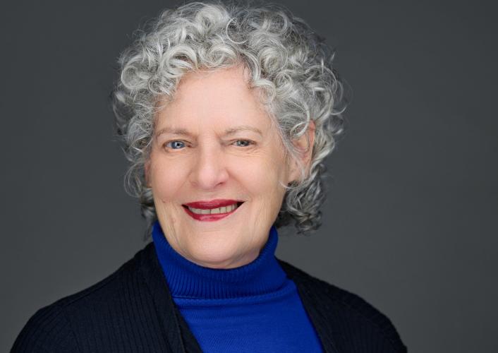 Rosemary Reed wearing a dark blue suit against a gray background.