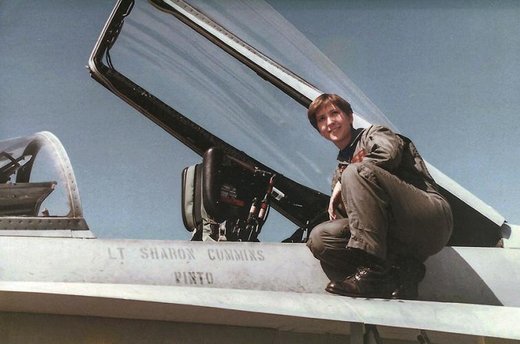 Sharon Deegan crouching on a fighter plane with the cockpit open. She is wearing a flight suit.